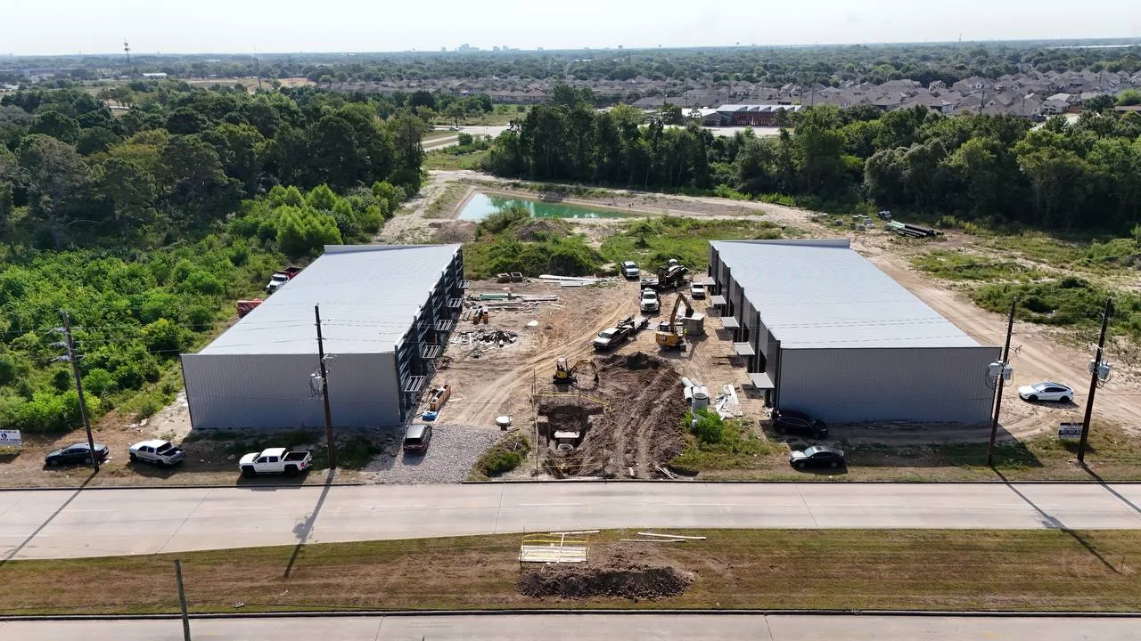 Aerial view of two parallel metal warehouse buildings with active underground utility work between them